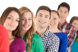 Waiting in line. Young people standing in a row and smiling at camera while isolated on white photo