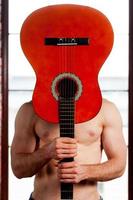 Guitar head. Close-up of man playing acoustic guitar while standing in front of the window photo