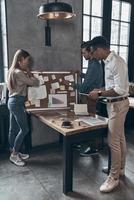 Full length of young coworkers in smart casual wear discussing business while working in office photo