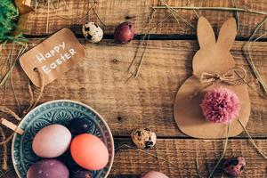 Happy Ester top view of colored Easter eggs and Easter decorations lying on wooden rustic table photo