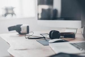 New innovations. Headphones and VR headset laying on the office desk and near laptop and computer photo