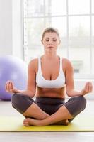 Staying calm. Beautiful mature woman mediating while sitting in lotus position photo