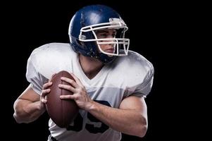 My favorite game.  American football player looking away and holding ball while standing against black background photo