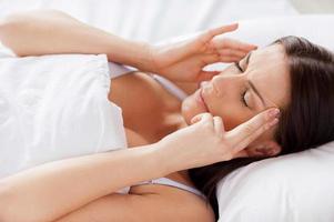 Woman with headache. Handsome young shirtless man holding hand in hair and keeping eyes closed while lying in bed photo