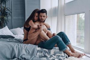 momentos de alegría. hermosa joven pareja semi-vestida abrazándose mientras pasa tiempo en el dormitorio foto