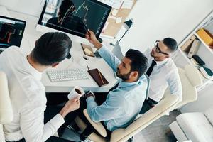 Ready to work hard. Top view of young modern men in formalwear working using computers while sitting in the office photo