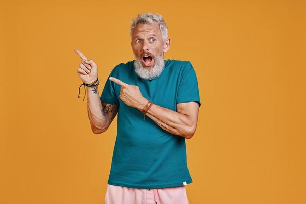 Surprised senior man pointing copy space and making a face