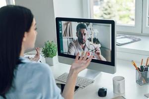 Young woman talking to collegue by video call while sitting in office photo