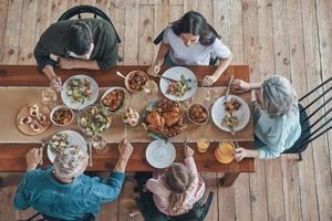 vista superior de la familia multigeneracional comunicándose y sonriendo mientras cenamos juntos foto