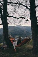 Real relaxation. Handsome young man lying in hammock while camping with his girlfriend photo