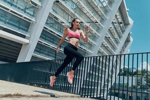 Beautiful young woman in sports clothing running outdoors photo