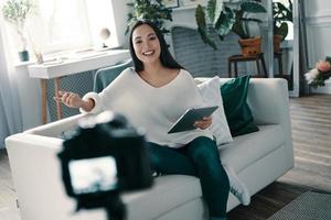 Beautiful influencer. Attractive young woman gesturing and smiling while making new video for her blog photo