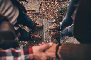 Love forever. Close up top view of modern young couple holding hands while standing in the woods photo