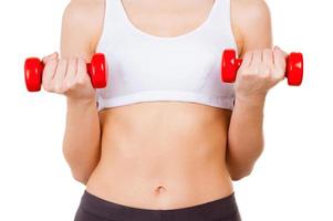 ejercicios con mancuernas. imagen recortada de una joven con ropa deportiva entrenando con pesas mientras está aislada en blanco foto