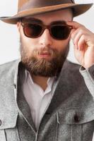 Trendy look. Close up portrait of handsome young man in casual wear adjusting his sunglasses photo