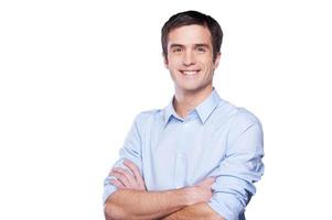 Confident businessman. Portrait of handsome young man in blue shirt looking at camera and keeping arms crossed while standing isolated on white photo