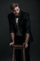 Serious look. Confident man in casual clothing looking at camera while posing against grey background photo