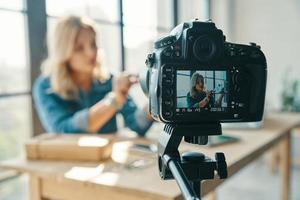 Beautiful young woman unpacking something while working in front of digital camera photo