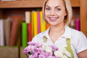 Beautiful florist. Beautiful young blond hair woman in apron holding bunch of flowers and smiling photo