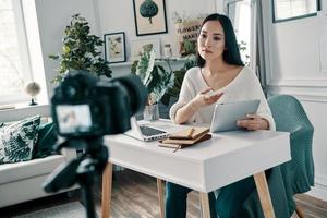 Talking about important things. Beautiful young woman explaining something while making new video for her blog photo