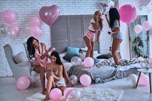 las niñas siempre son niñas. cuatro atractivas mujeres jóvenes en pijama sonriendo durante un tratamiento de belleza mientras pasan tiempo en el dormitorio foto