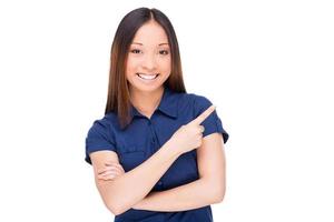 Pointing copy space. Beautiful young Asian woman pointing away and smiling while standing isolated on white photo