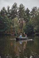 Enjoying time together. Beautiful young couple enjoying romantic date and smiling while rowing a boat photo