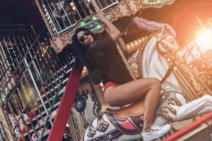 Beauty on merry-go-round. Attractive young mixed raced woman in red bikini riding merry-go-round photo