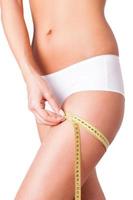 Measuring her haunch. Cropped image of woman in white panties measuring her haunch while standing isolated on white photo