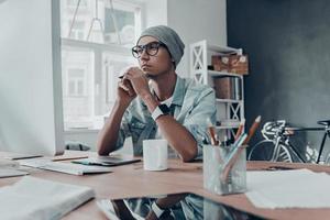 Thinking about every detail. Handsome young man looking at computer monitor while sitting at his working place in creative office photo
