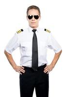 Confident and experienced pilot. Confident male pilot in uniform holding hands on hip while standing against white background photo