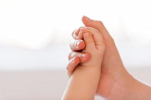 I am always near. Close-up of mother hand holding hand of her little baby photo