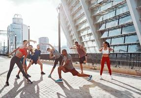 Full length of people in sports clothing warming up and stretching while exercising outdoors photo