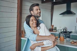 Beautiful young couple smiling and bonding while spending time in the kitchen photo