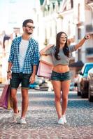 We have to visit that shop Full length of young loving couple holding shopping bags and looking away while walking along the street photo