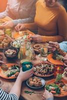 Dinning together. Top view of group of people having dinner together while sitting at the rustic wooden table photo