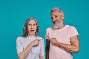 Playful senior couple looking at camera and pointing at each other photo