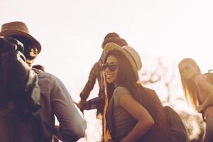 Travelling with friends. Group of young people with backpacks walking together and looking happy photo