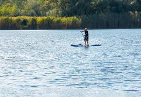 Dnipro, Ukraine - 09.08.2022 A sports man of advanced years rides a sapboard on the river. Photo set. City water activities.