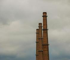 Air pollution from smoke coming out of three factory chimneys. The concept of air pollution, environmental problems. photo