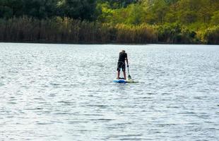 Dnipro, Ukraine - 09.08.2022 A sports man of advanced years rides a sapboard on the river. Photo set. City water activities.