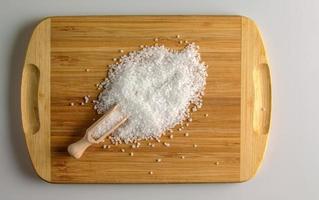 Salt in a wooden spoon on a wooden kitchen board. Large pieces of sea salt in a small wooden spoon photo