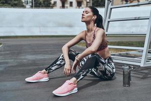 Beautiful young woman in sports clothing running while exercising outdoors photo