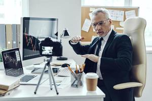 Senior man in elegant business suit using modern technologies while making social media video photo