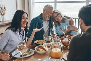 feliz familia multigeneracional comunicándose y sonriendo mientras cenamos juntos foto