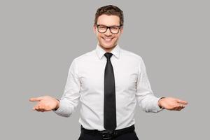 bienvenido a bordo a un joven apuesto con camisa y corbata estirando los brazos y sonriendo mientras se enfrenta a un fondo gris foto