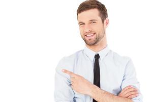 Businessman pointing copy space. Handsome young man in shirt and tie looking at camera and pointing away while standing isolated on white backgroundBusinessman pointing copy space. Handsome young man in shirt and tie looking at camera and pointing away wh photo