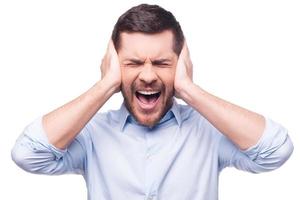 This is too loud Frustrated young man in formalwear holding head in hands and keeping eyes closed while standing against white background photo