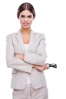 So much beauty in business. Confident young businesswoman keeping arms crossed and smiling while standing against white background photo