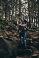 Helping hand. Full length of young couple holding hands and moving up while hiking together in the woods photo